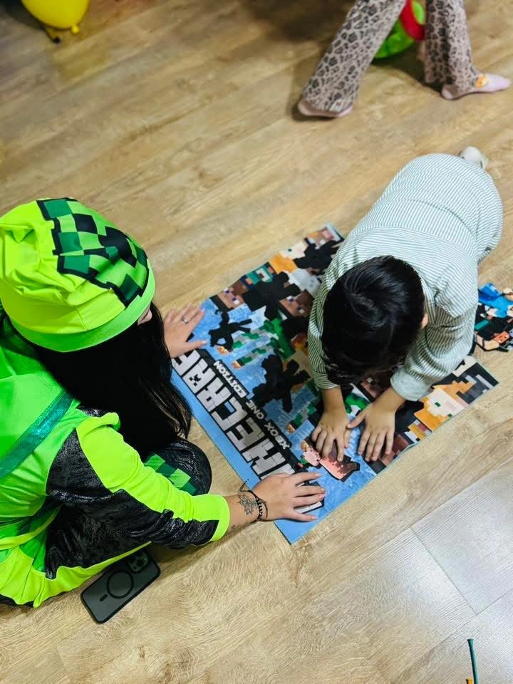 animatoare in costum verde si copil puzzle petrecere aniversara